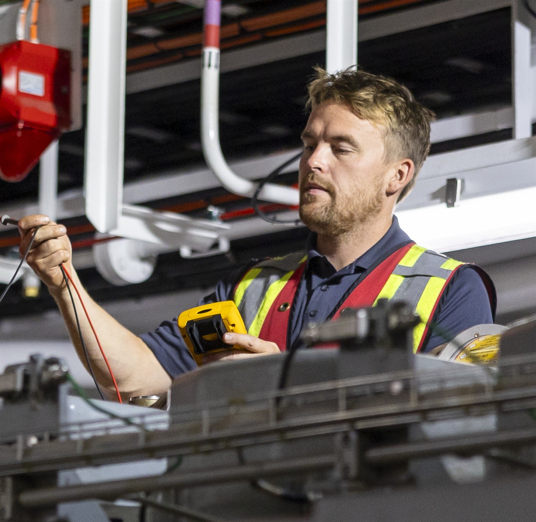 Technician using test equipment among vessel machinery and pipework